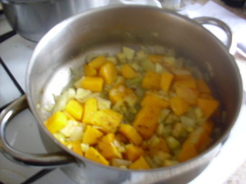 A pan on stove with beans and cut up pumpkin and sweet potato
