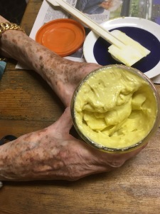 Elderly woman's hands around a jar of thick, yellow, unctuous home made mayonnaise