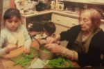 Grandmother and granddaughter shelling peas at kitchen table, both focused on task